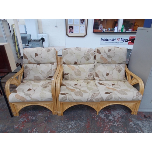 14 - A TWO PIECE CANE CONSERVATORY SET COMPRISING OF A TWO SEATER SOFA AND AN ARM CHAIR WITH BEIGE UPHOLS... 