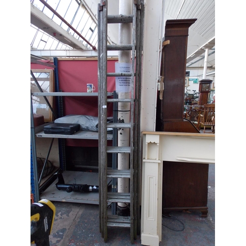 35 - A SET OF WOOD AND ALUMINIUM 27 RUNG TRIPLE EXTENDABLE WORK LADDERS