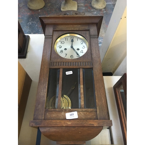 389 - AN OAK WALL CLOCK WITH PENDULUM