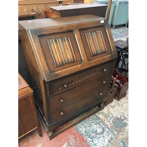 537 - A DARK OAK BUREAU WITH THREE DRAWERS AND A FALL FRONT