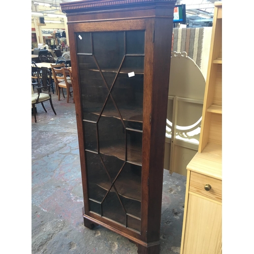 553A - A MAHOGANY FREE STANDING CORNER CABINET WITH ONE GLASS DOOR AND FOUR SHELVES