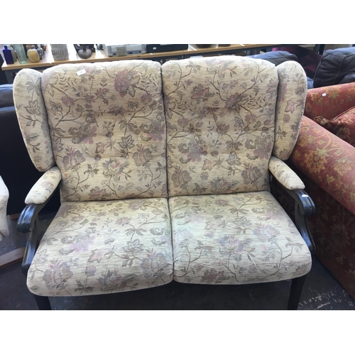 661 - A BEIGE FLORAL UPHOLSTERED TWO SEATER WINGBACK SOFA