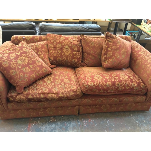 662 - A BURGUNDY FLORAL PATTERNED THREE SEATER SOFA WITH CUSHIONS