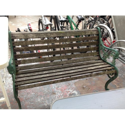 40 - A WOODEN SLATTED TWO SEATER GARDEN BENCH WITH CAST IRON ORNATE ENDS TOGETHER WITH A GOOD QUALITY FOL... 