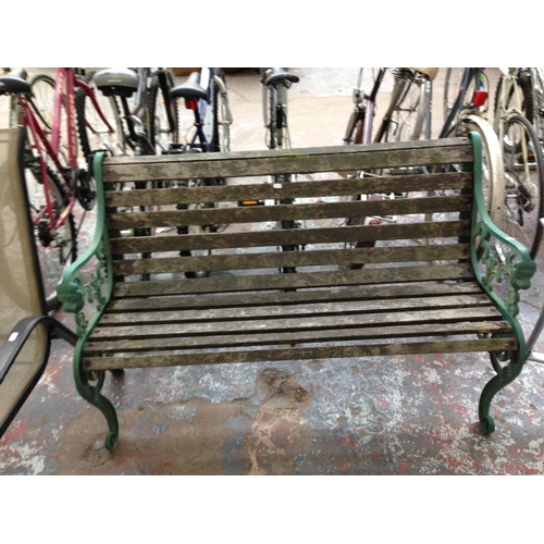 40 - A WOODEN SLATTED TWO SEATER GARDEN BENCH WITH CAST IRON ORNATE ENDS TOGETHER WITH A GOOD QUALITY FOL... 