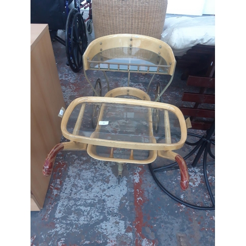 23 - A VINTAGE THREE WHEELED DRINKS TROLLEY WITH GLASS SHELVES AND REMOVABLE TRAY