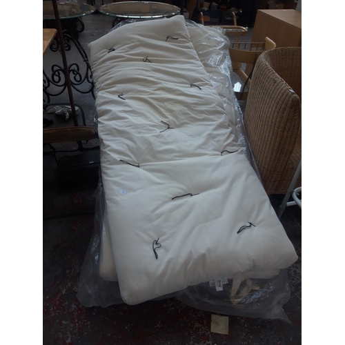 36 - TWO FOLDING WOODEN FUTONS WITH CREAM UPHOLSTERY