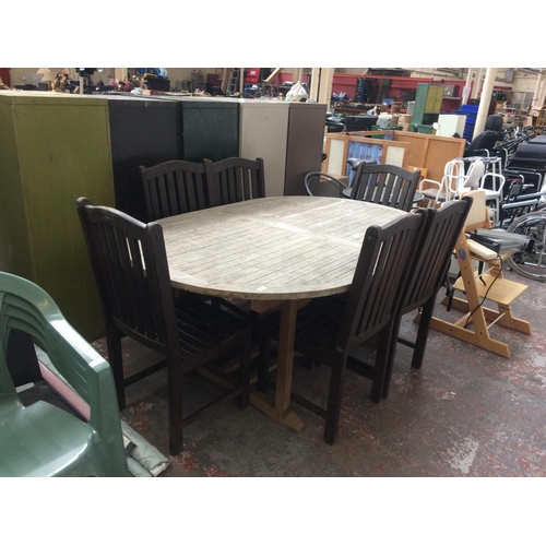 37 - A GOOD QUALITY TEAK OVAL PATIO TABLE WITH SIX DARK WOOD CHAIRS