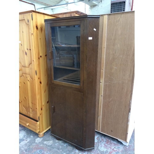 556 - AN OAK CORNER CABINET WITH ONE LOWER DOOR AND ONE UPPER GLAZED DOOR