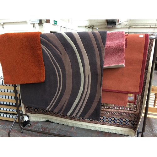 567 - FOUR MIXED RUGS TO INCLUDE AN ORANGE RUG, BROWN RUG, PINK RUG AND A FLORAL RUG