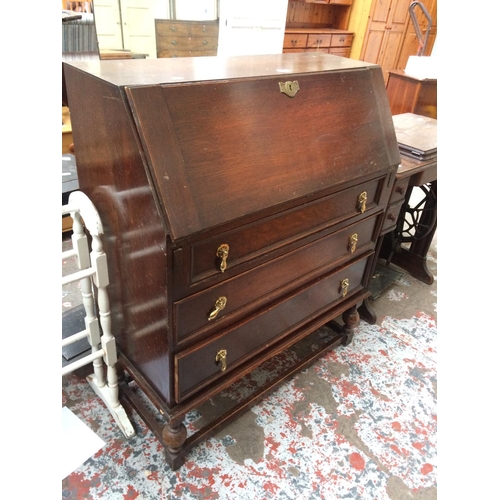 600 - AN OAK BUREAU WITH THREE DRAWERS AND FALL FRONT