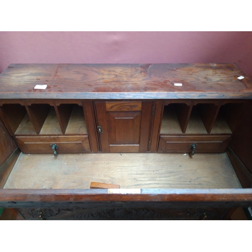 1117 - A JACOBEAN REVIVAL HEAVILY CARVED OAK BUREAU WITH TWO LOWER DOORS, TWO SHORT DRAWERS AND ONE LONG DR... 