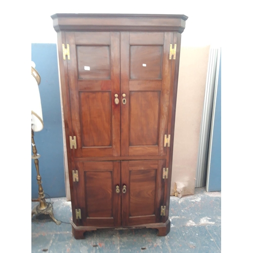 1125A - A GEORGIAN FLAMED MAHOGANY CORNER CUPBOARD WITH TWO LONG UPPER AND TWO SHORT LOWER DOORS WITH BRASS ... 