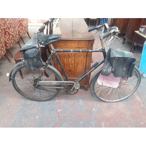 1110A - A VINTAGE BLACK RALEIGH MEN'S TOWN BIKE WITH FRONT AND REAR PANNIERS, SPRUNG SADDLE AND 3 SPEED STUR... 