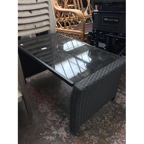 39 - A RECTANGULAR BLACK PLASTIC RATTAN COFFEE TABLE WITH METAL AND GLASS TOP