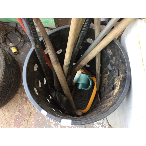 121 - A PLASTIC DUSTBIN CONTAINING GARDEN RAKE, SPADE, FIRE SHOVEL, BOW SAW ETC