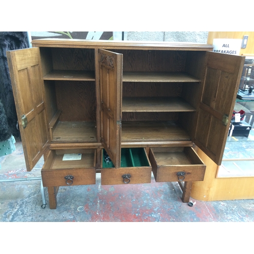 237 - A GOOD QUALITY GOLDEN OAK CABINET WITH THREE DOORS AND THREE DRAWERS SET UPON A STRETCHER BASE (MEAS... 