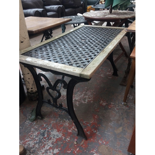 23 - A RECTANGULAR CAST IRON ORNATE GARDEN TABLE WITH CAST IRON TOP IN TIMBER SURROUND