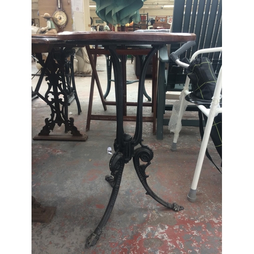 26 - A CAST IRON ORNATE CIRCULAR PEDESTAL TABLE WITH WOODEN TOP