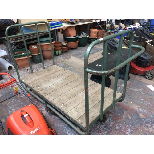 169 - A GREEN METAL FOUR WHEELED WAREHOUSE TROLLEY