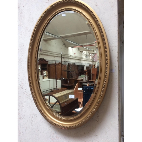 574 - A VINTAGE GILT FRAMED BEVEL EDGE OVAL MIRROR