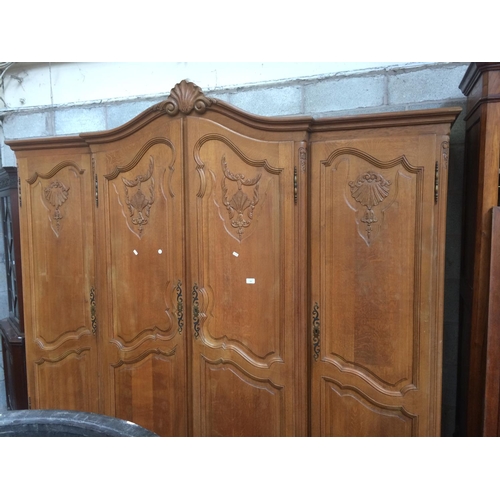 590 - A GOOD QUALITY LARGE FRENCH CARVED OAK WARDROBE WITH FOUR DOORS ON ORNATE SUPPORTS (MEASURING 85