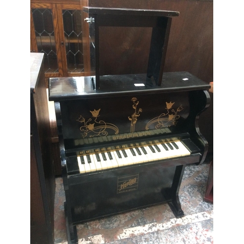 603 - A BLACK PAINTED STRADIVARIUS MINIATURE PIANO AND STOOL