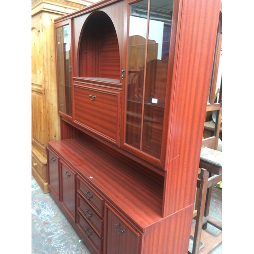 712 - A MODERN MAHOGANY EFFECT WALL UNIT WITH THREE LOWER DOORS, THREE DRAWERS, TWO UPPER GLAZED DOORS AND... 