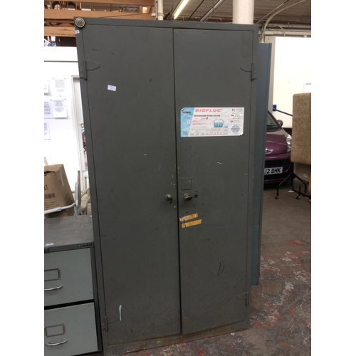 25 - A GREY METAL TWO DOOR OFFICE STORAGE CABINET CONTAINING A LARGE QUANTITY OF BOOKS