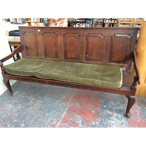 306 - A LARGE 18TH CENTURY OAK SETTLE WITH FIVE PANELS AND GREEN UPHOLSTERED CUSHION