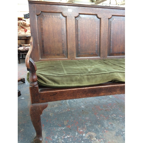 306 - A LARGE 18TH CENTURY OAK SETTLE WITH FIVE PANELS AND GREEN UPHOLSTERED CUSHION