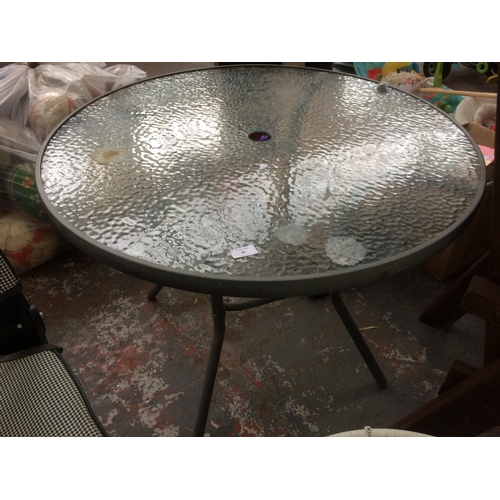 35 - A GREY METAL CIRCULAR GLASS TOPPED PATIO TABLE AND A CAST IRON PARASOL BASE