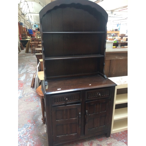 538 - AN ERCOL OLD COLONIAL ELM WELSH DRESSER WITH TWO DOORS, TWO DRAWERS, UPPER PLATE RACK AND CONTENTS