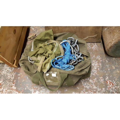 134 - A GREEN MILITARY CANVAS BAG CONTAINING BUNGEE CORDS, ROPE, DOG TETHERS ETC.