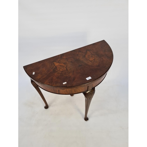 54 - A BURR WALNUT QUEEN ANNE STYLE FOUR LEGGED HALF MOON HALL/CARD TABLE WITH GREEN BAIZE TOP, CONCEALED... 