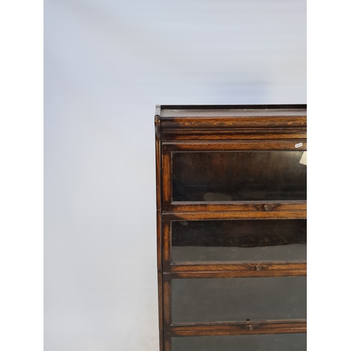 11 - A 1920'S GLOBE WERNICKE STYLE OAK FOUR TIER STACKING BOOKCASE WITH GLAZED FRONTS AND BRASS HANDLES -... 