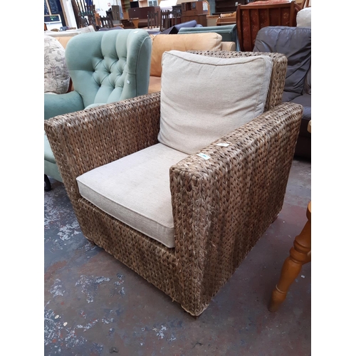 767 - A WICKER CONSERVATORY ARMCHAIR WITH CREAM UPHOLSTERED CUSHIONS