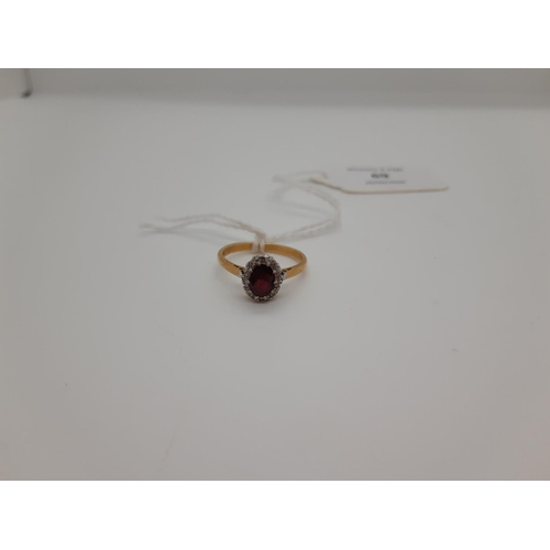 69 - A HALLMARKED 18CT YELLOW GOLD LADIES RING WITH OVAL DEEP RED GARNET STONE CENTRE SURROUNDED BY MINIA... 