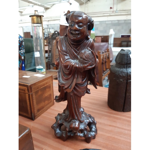 110 - A 19TH CENTURY ORIENTAL CARVED HARDWOOD FIGURE OF AN ELDER HOLDING FOOD BASKET