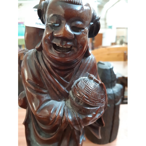 110 - A 19TH CENTURY ORIENTAL CARVED HARDWOOD FIGURE OF AN ELDER HOLDING FOOD BASKET