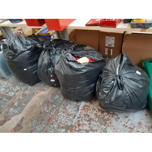 412 - FOUR LARGE BAGS CONTAINING WOOLEN BLANKET, CLOTHING, CUSHIONS ETC.