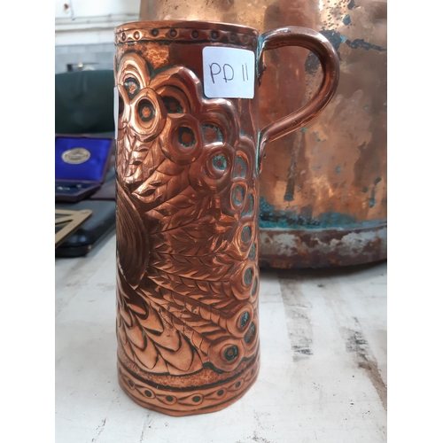 99 - AN ARTS AND CRAFTS EMBOSSED COPPER JUG WITH WELL DETAILED PEACOCK DESIGN AND UPPER HANDLE