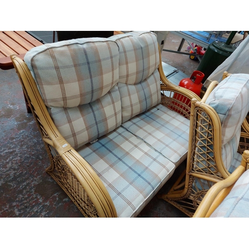 31 - A THREE PIECE CANE CONSERVATORY SET COMPRISING TWO SEATER SOFA AND TWO ARMCHAIRS WITH CHECKED UPHOLS... 