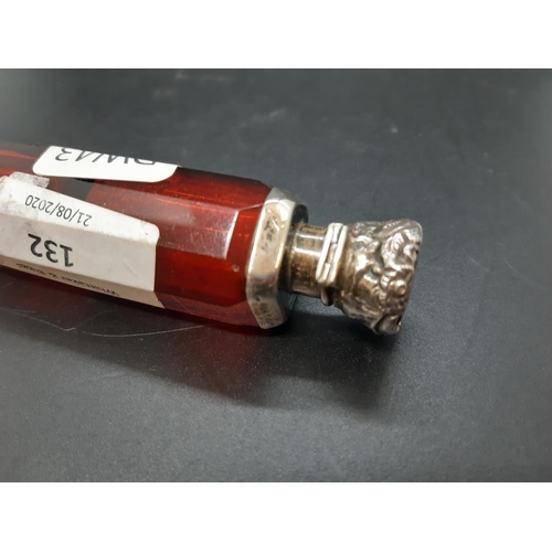 132 - A double ended ruby glass scent bottle with embossed white metal tops with repeated foliate design, ... 