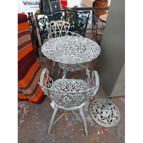 277 - A four piece cast aluminium patio set comprising of circular ornate table, two matching armchairs an... 