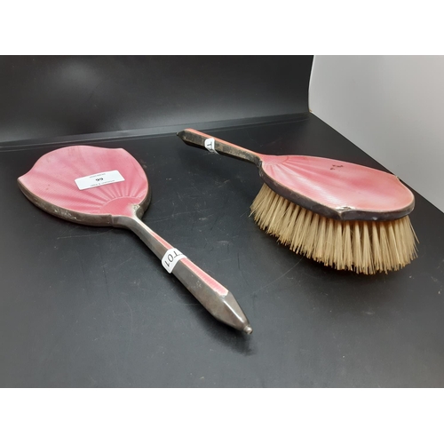 66 - A two piece hallmarked Birmingham silver and pink enamel dressing table set comprising hair brush an... 