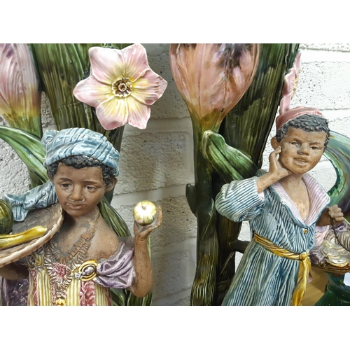 39 - A pair of tall Art Nouveau Majolica floor vases featuring tall flowers and buds, each having a Black... 