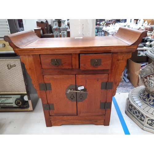 111 - A modern oriental influenced hardwood miniature cabinet/stool with two doors, two drawers and aged b... 