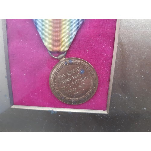 57 - A gilt framed WWI presentation medal set with two medals, one being a service medal and the other a ... 