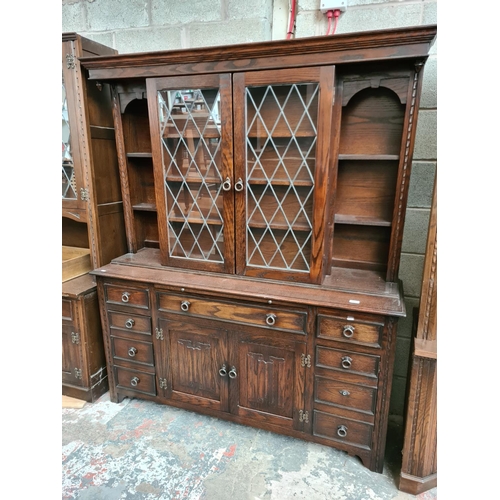 495 - A Jaycee oak dresser with two upper glazed doors, nine drawers and two lower cupboard doors - measur... 